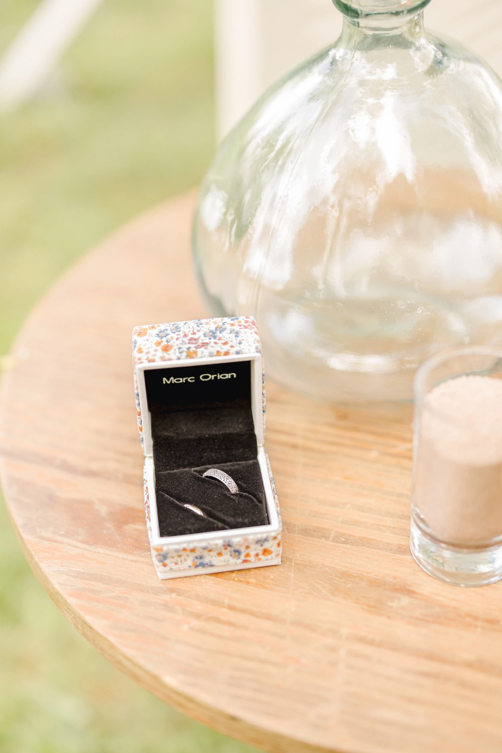 Écrin d'alliance posé sur une table en bois naturel avec décoration florale minimaliste