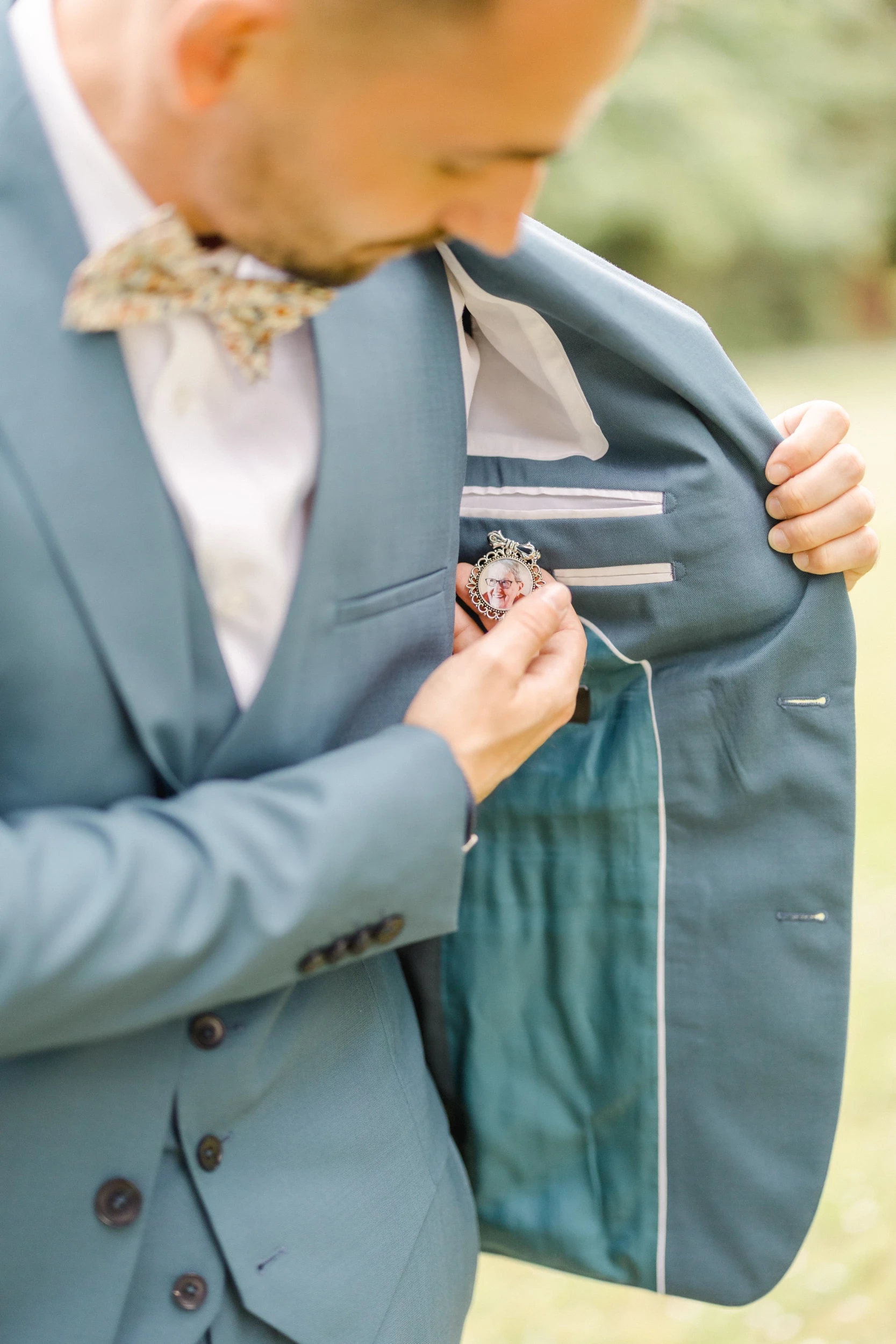 Marié ajustant sa boutonnière florale sur son costume gris lors de ses préparatifs de mariage