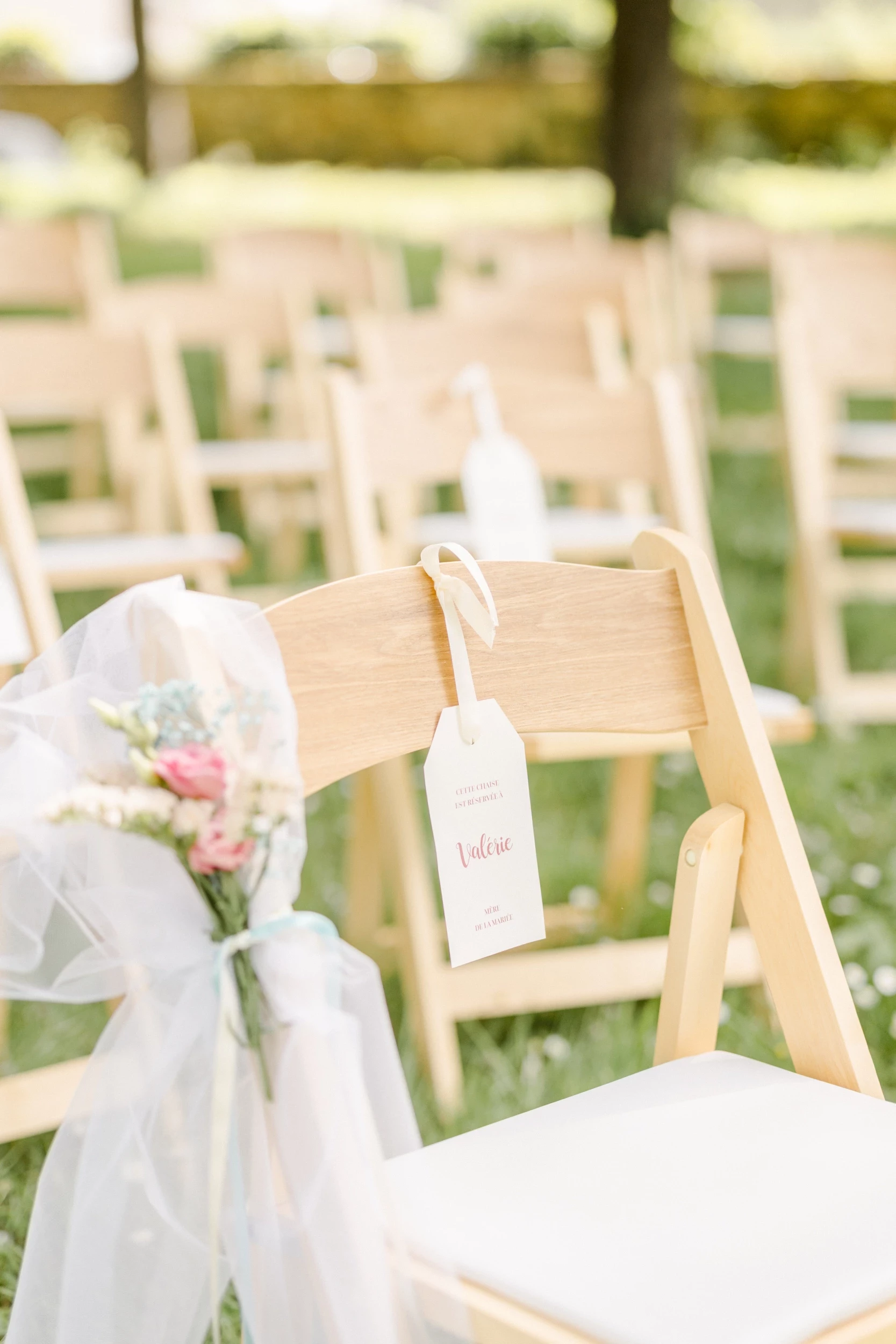 Chaises blanches décorées de voile et fleurs pour cérémonie de mariage en extérieur