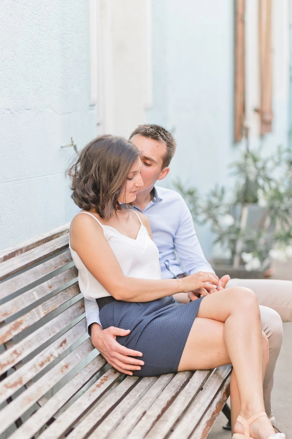 Séance couple tendresse sur banc bois, complicité et douceur dans la lumière dorée, ambiance intime et élégante en extérieur