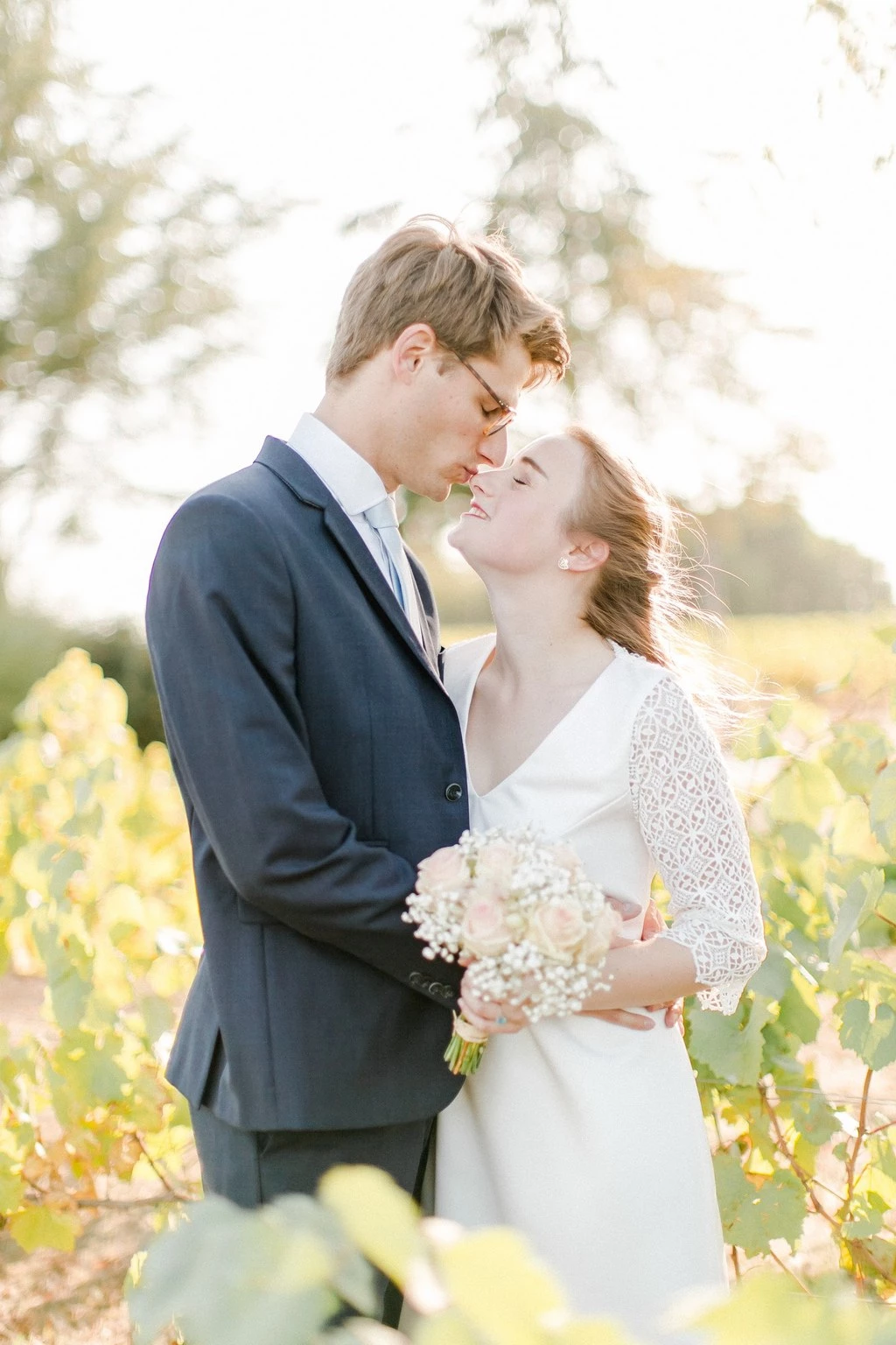 Couple de mariés dans un vignoble ensoleillé, échangeant un regard tendre et complice