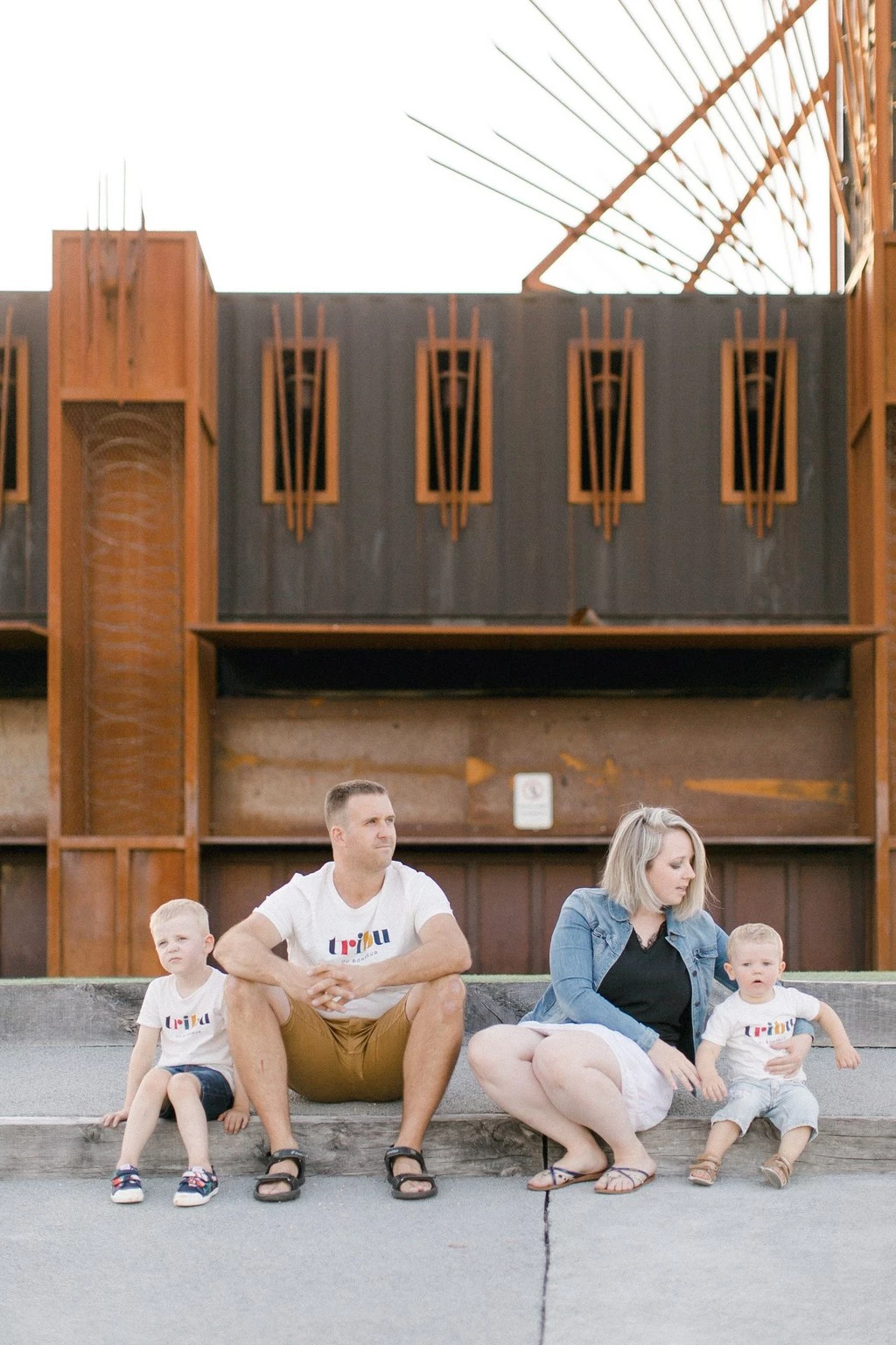 Séance famille complice devant architecture vintage, parents et deux enfants en tenues assorties, lumière dorée et naturelle, ambiance tendresse et authenticité