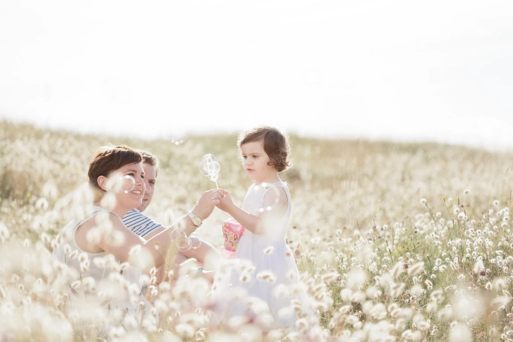 Séance famille en plein air : deux enfants souriants dans un champ de fleurs blanches, complicité et douceur, lumière dorée naturelle, Vendée
