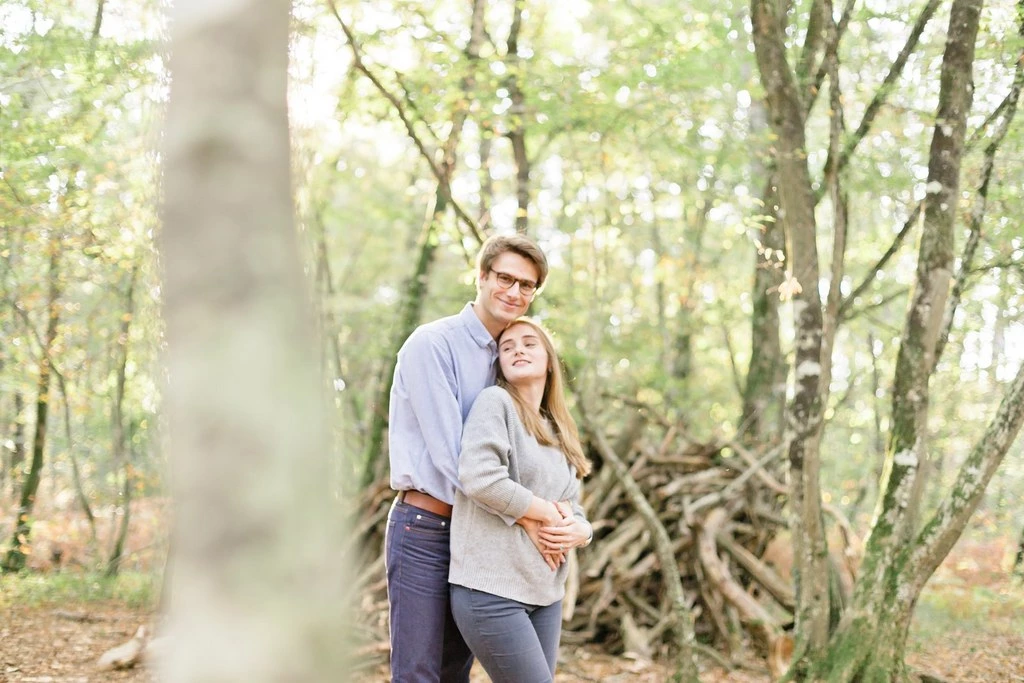 Couple enlacé en forêt lors d'une séance photo couple, lumière naturelle douce