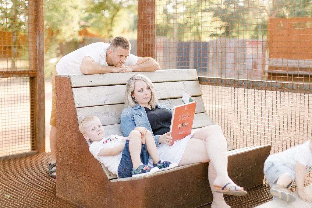 Séance famille en extérieur : père et mère complices avec enfant sur banc en bois, lumière dorée, ambiance tendre et authentique en Vendée
