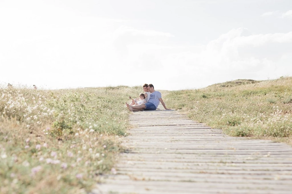 Couple enlacé sur une passerelle en bois au cœur d'une prairie fleurie, moment intime et tendre baigné de lumière douce en Vendée