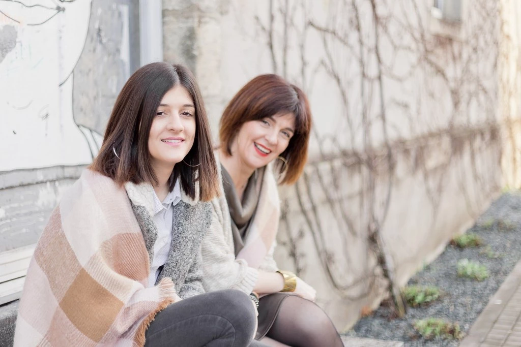 Séance portrait de deux femmes complices assis contre un mur de pierre, ambiance intime et élégante en lumière naturelle douce