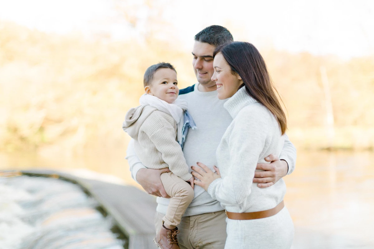 Séance photo famille en extérieur : parents et enfant en tenue élégante, complicité tendre et lumière dorée, ambiance intemporelle et raffinée