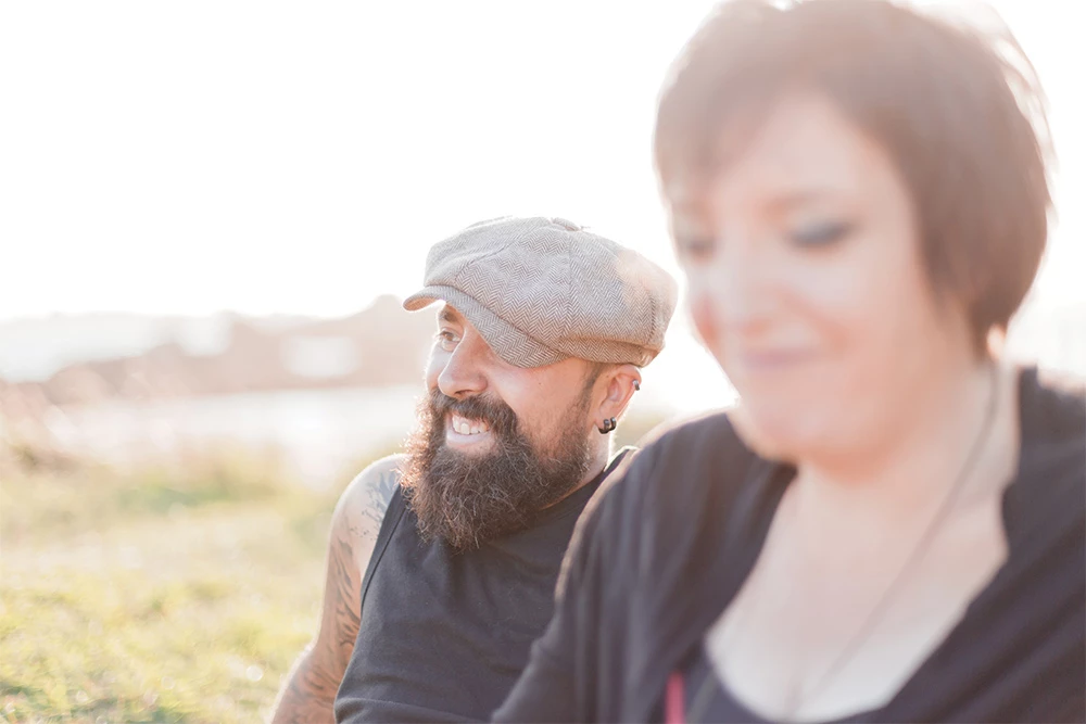 Séance portrait couple en extérieur, deux personnes complices dans la lumière dorée d'un champ, ambiance intime et authentique en Vendée