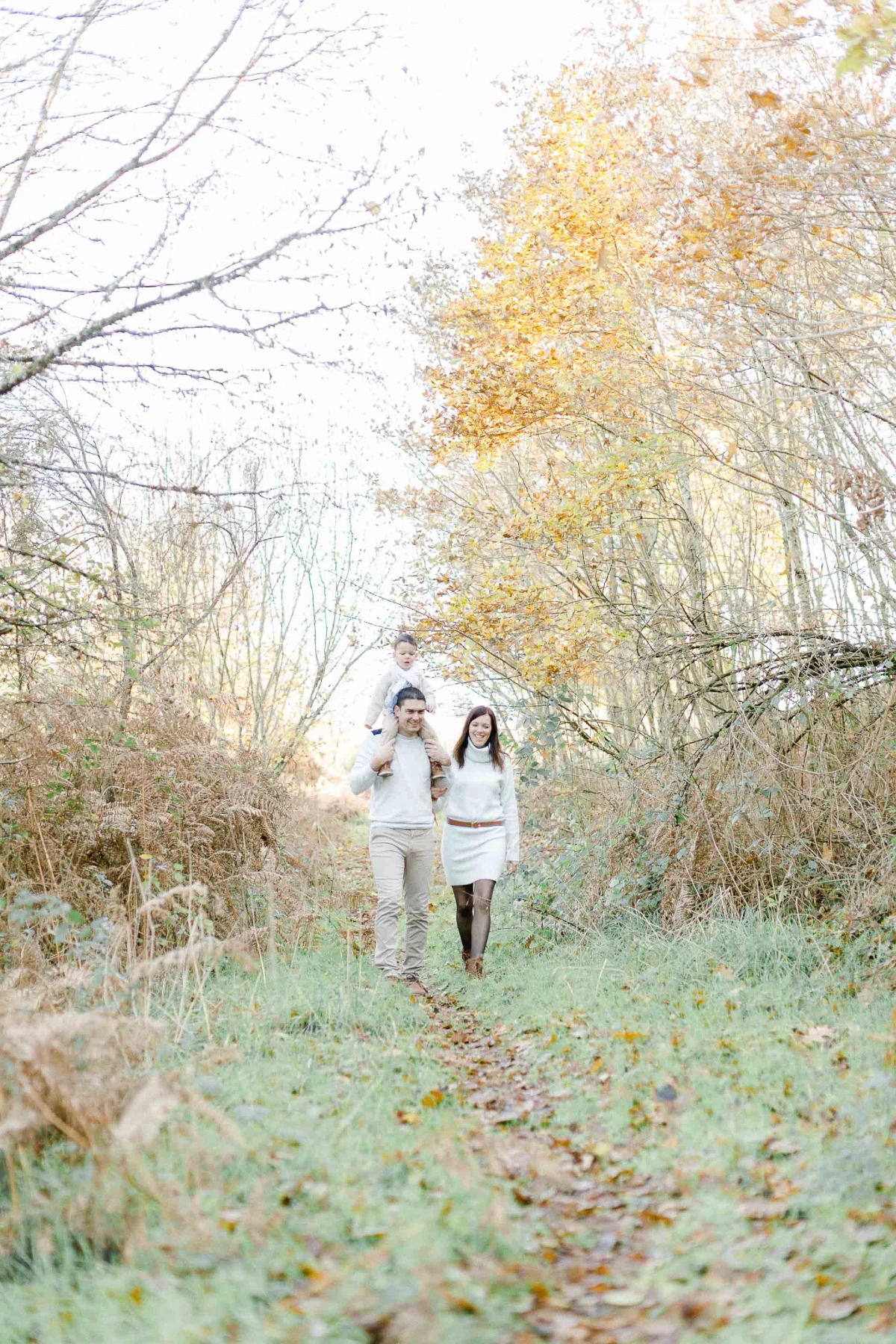 Séance photo couple automnal en nature - deux personnes marchant main dans la main sur un sentier forestier aux teintes dorées et ocre, ambiance intime et tendre