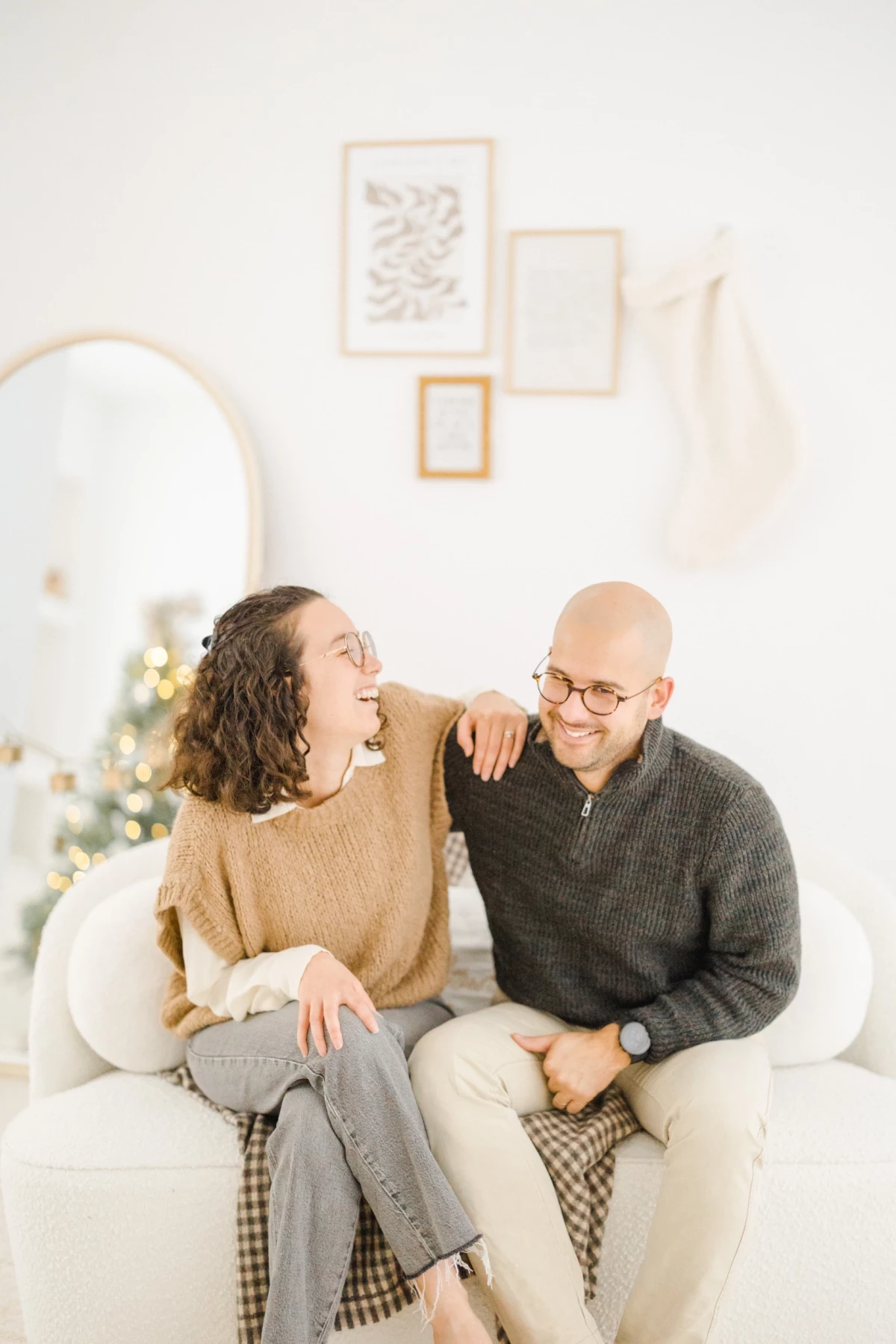 Couple complice assis sur un canapé blanc dans un intérieur cosy décoré pour Noël