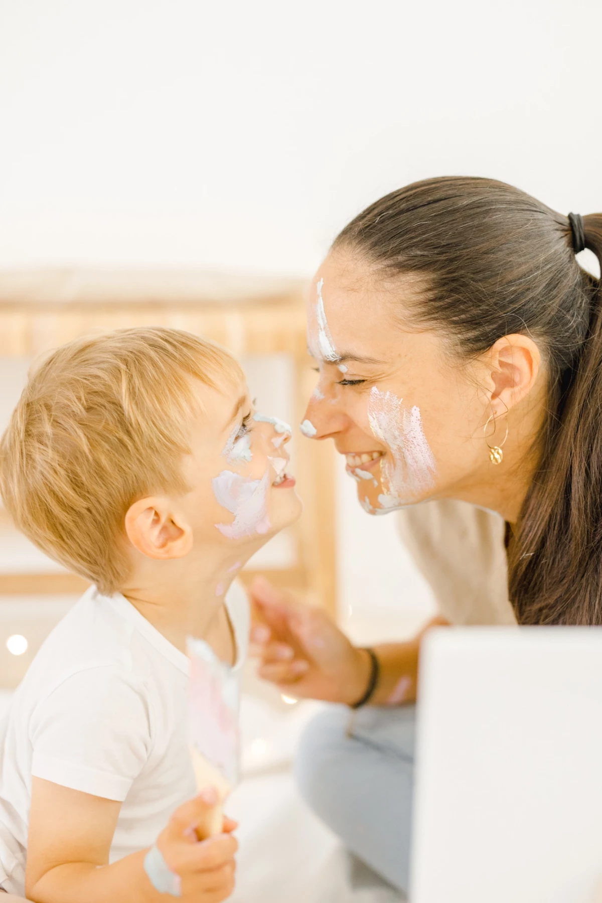 Mère et enfant partageant un moment complice lors du bain, visages recouverts de mousse blanche