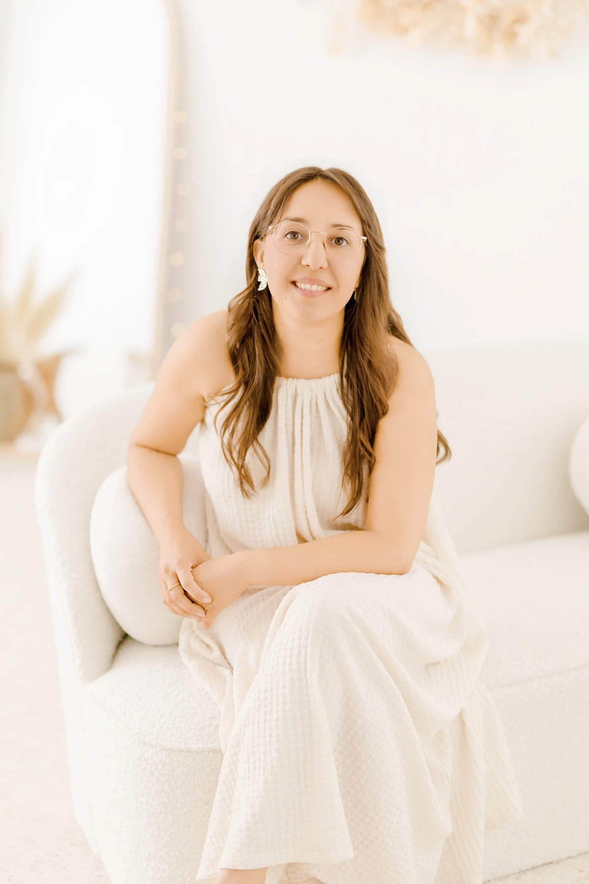 Cécile Potier, photographe grossesse et naissance en Vendée, sourit assise sur le canapé de son studio.