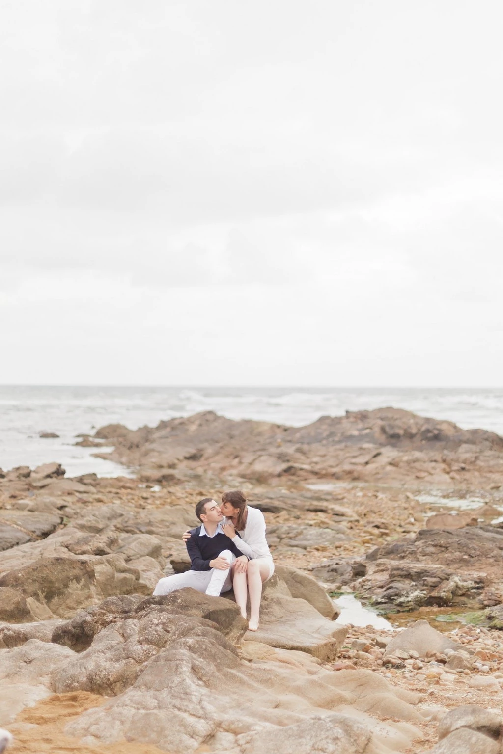 Séance couple sur rochers côtiers vendéens, moment de tendresse et complicité face à l'océan, ambiance intemporelle et lumière douce