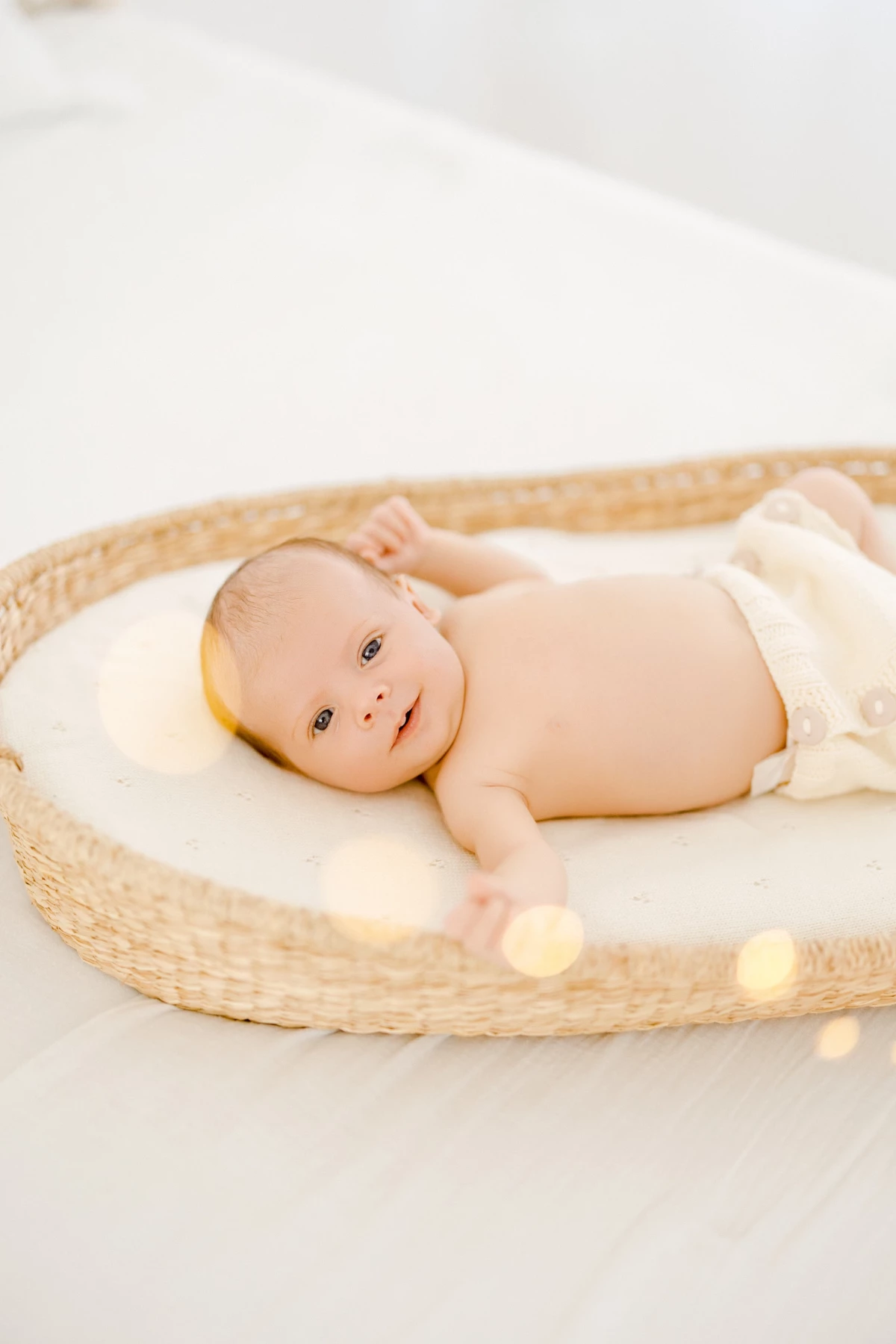 Séance nouveau-né en studio : bébé allongé dans un panier en osier sur fond blanc, ambiance douce et naturelle
