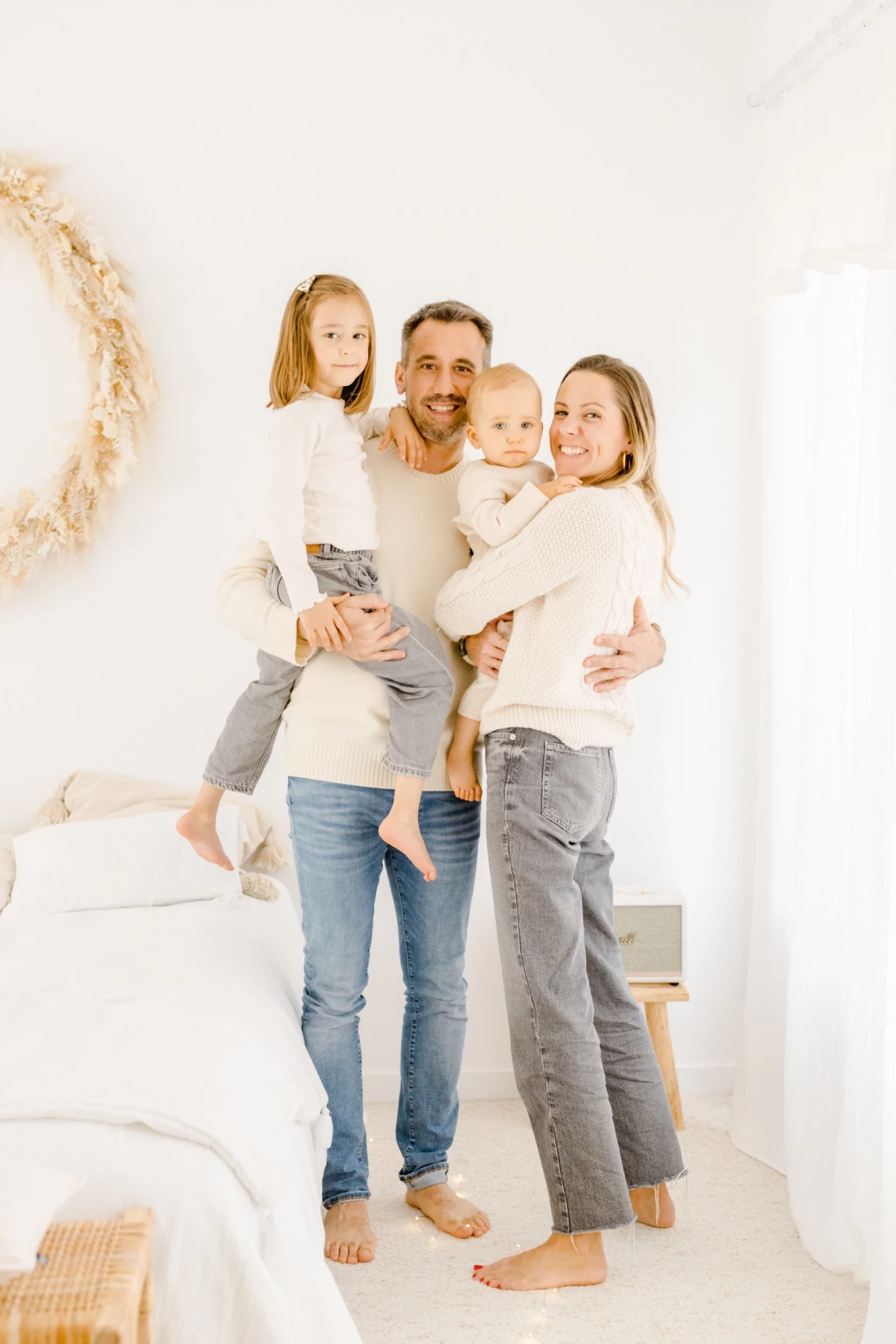 Famille heureuse réunie dans un intérieur lumineux blanc, parents et deux enfants enlacés