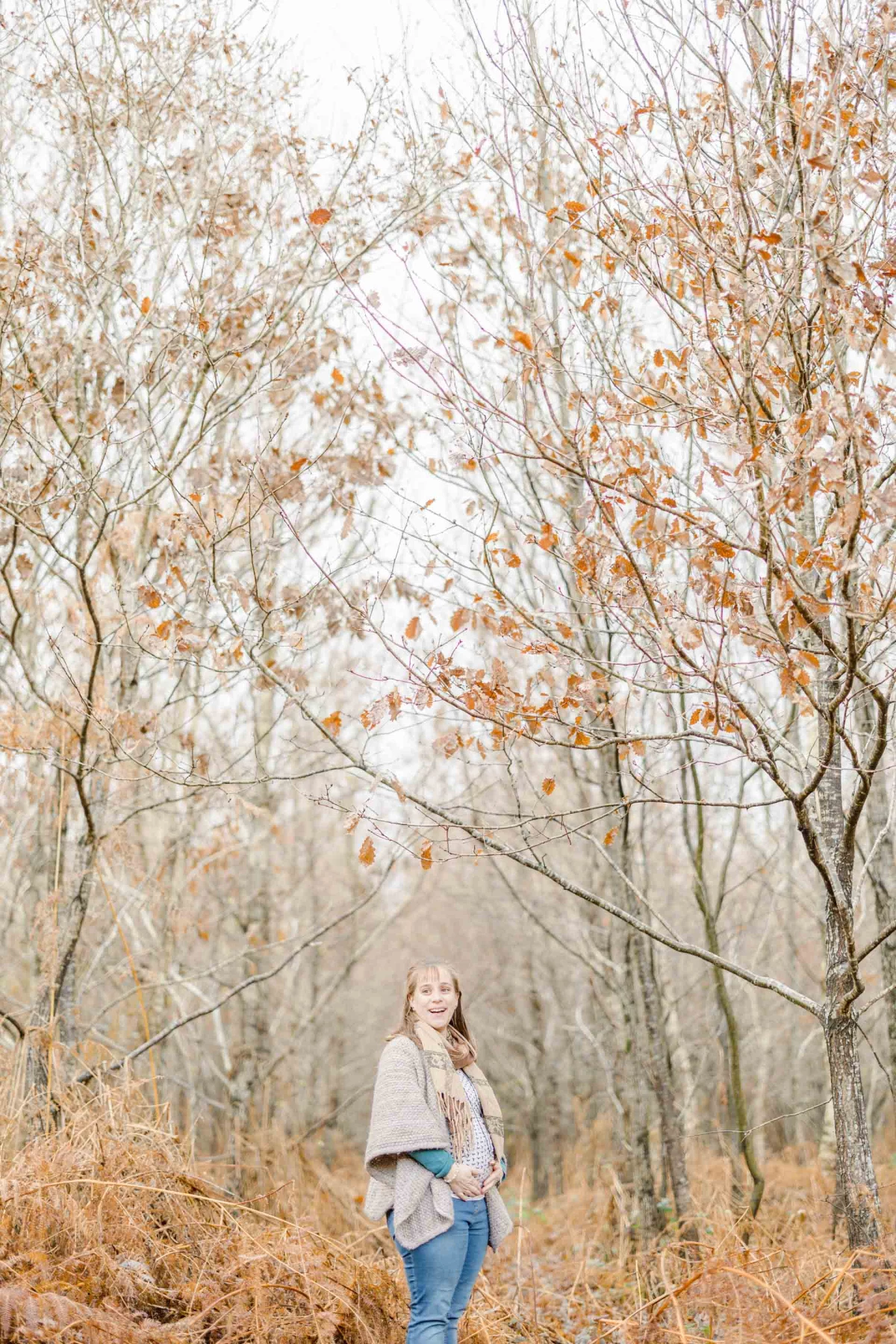 Portrait d'automne d'une jeune fille souriante sous une voûte de feuillages dorés, ambiance chaleureuse et intemporelle en forêt