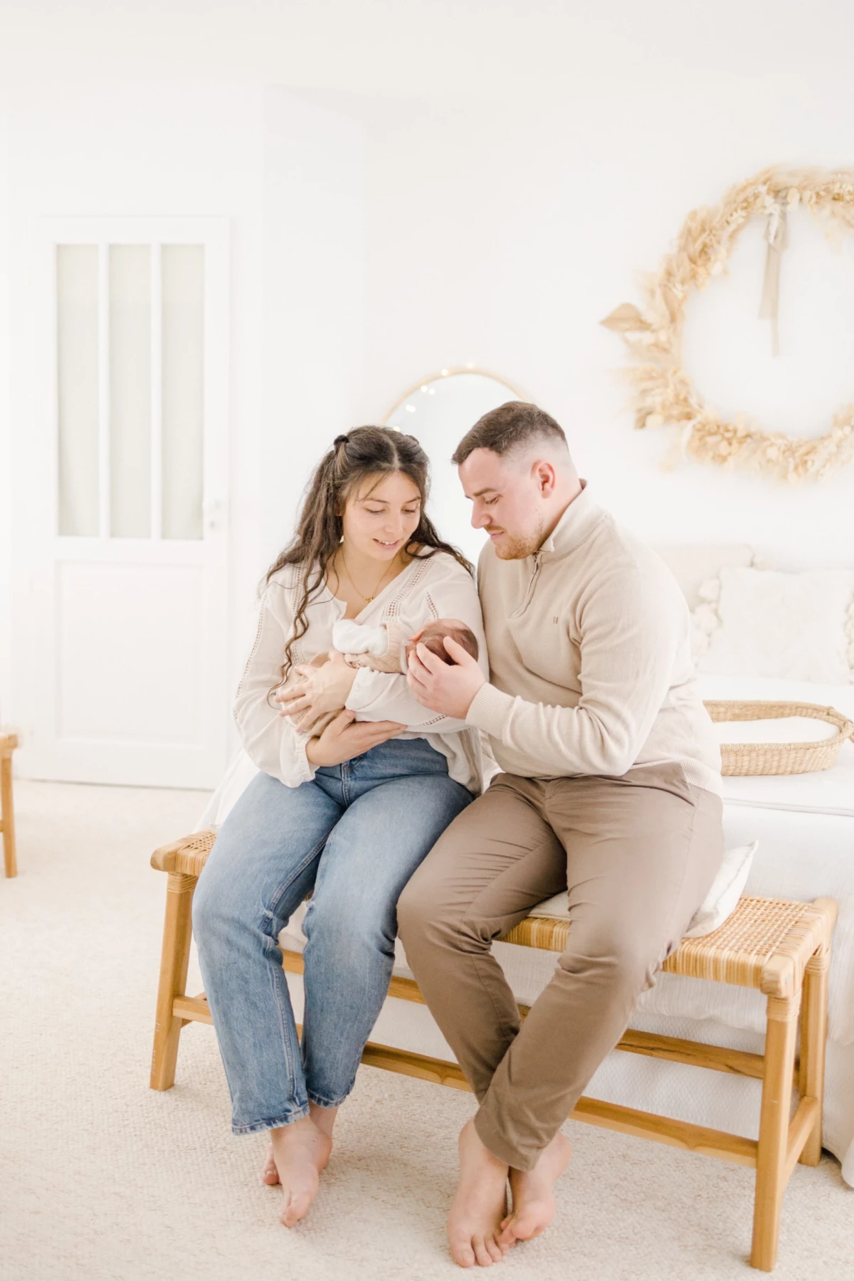Séance naissance en studio : jeunes parents enlacent leur nouveau-né dans une lumière douce et épurée, tendresse et amour partagés