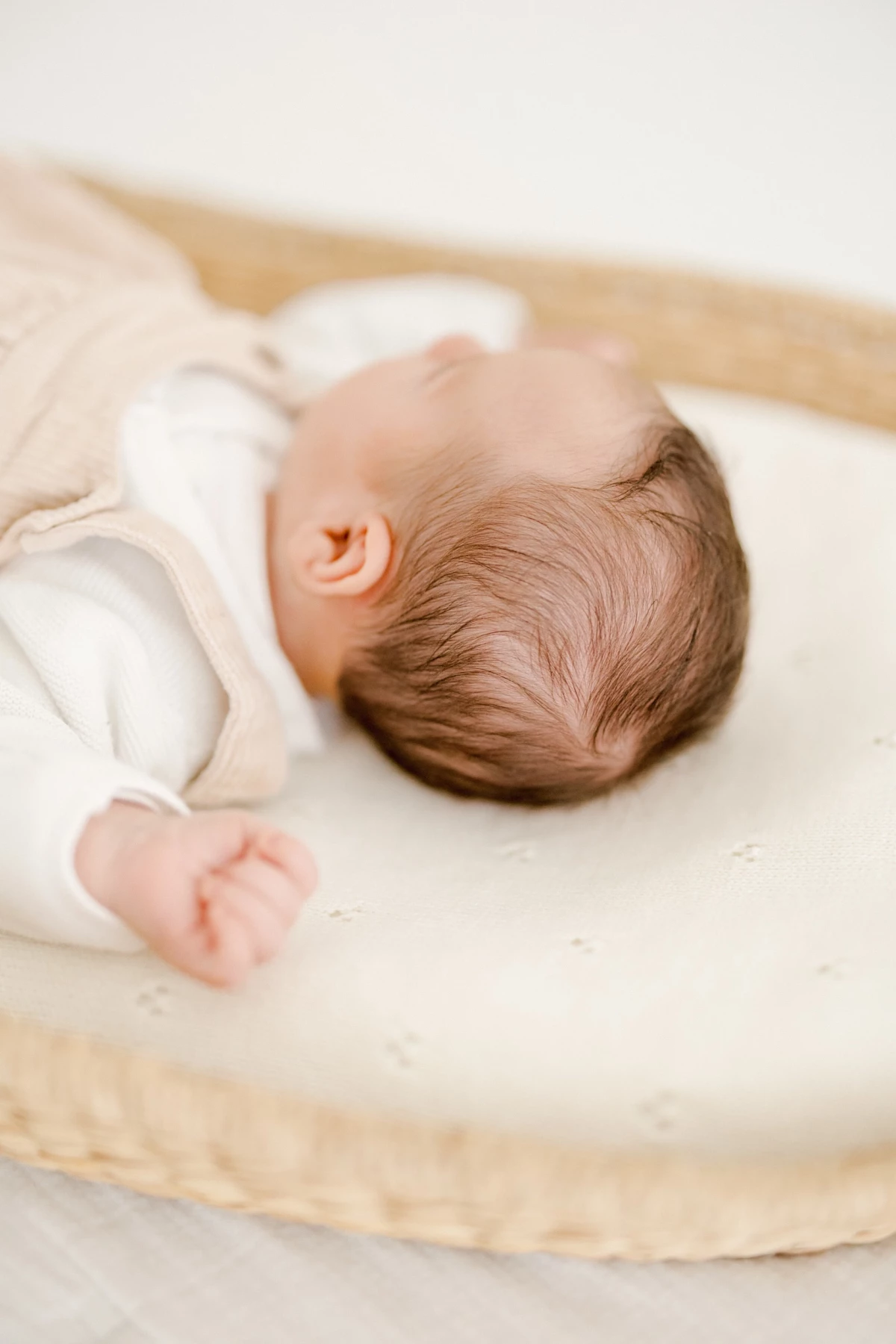 Séance nouveau-né en studio : bébé allongé paisiblement dans un panier tressé, ambiance douce et épurée en Vendée