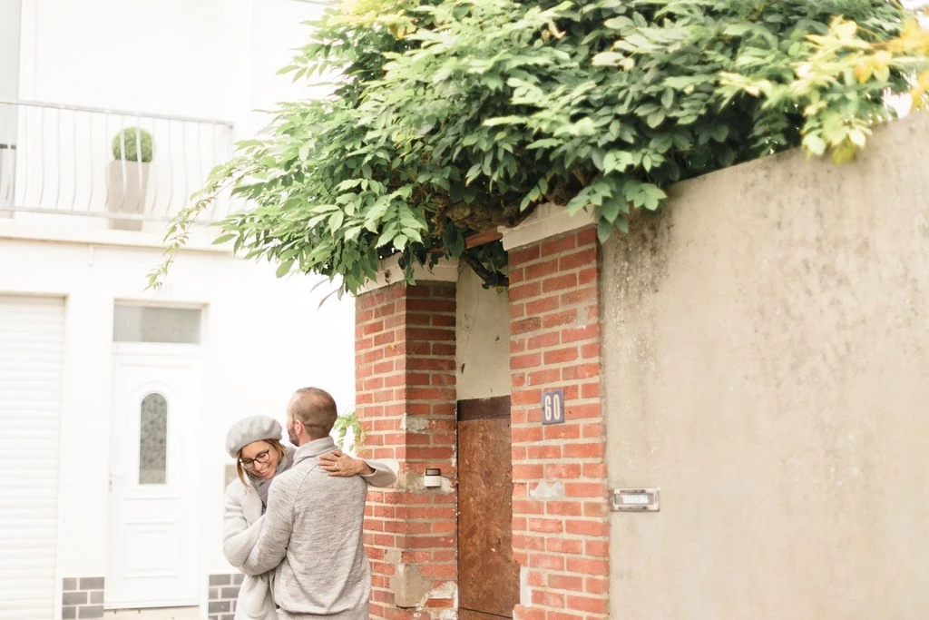 Séance photo famille en extérieur : père tenant son enfant devant une porte en brique, lumière dorée, moment de tendresse et complicité