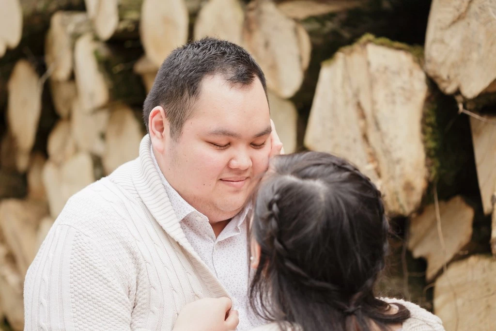 Séance couple tendresse : homme et femme en étreinte douce devant mur pierre, lumière naturelle, intimité authentique et complicité émotionnelle
