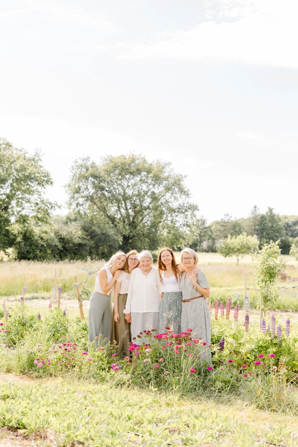 Portrait de famille multigénérationnelle réunie dans un jardin fleuri, entourée de roses et de lupins