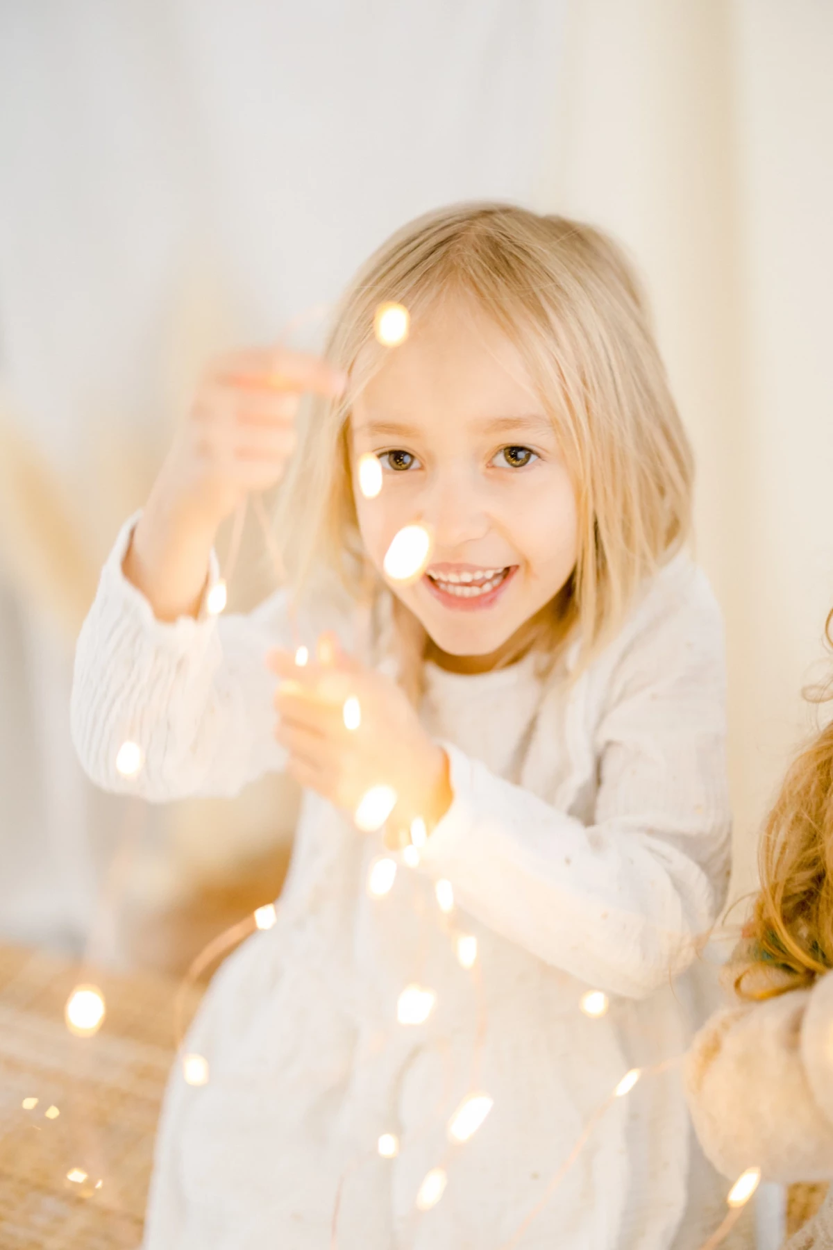 Séance enfant en studio : fillette blonde souriante dans une ambiance lumineuse et festive, capturant la joie et la douceur de l'enfance