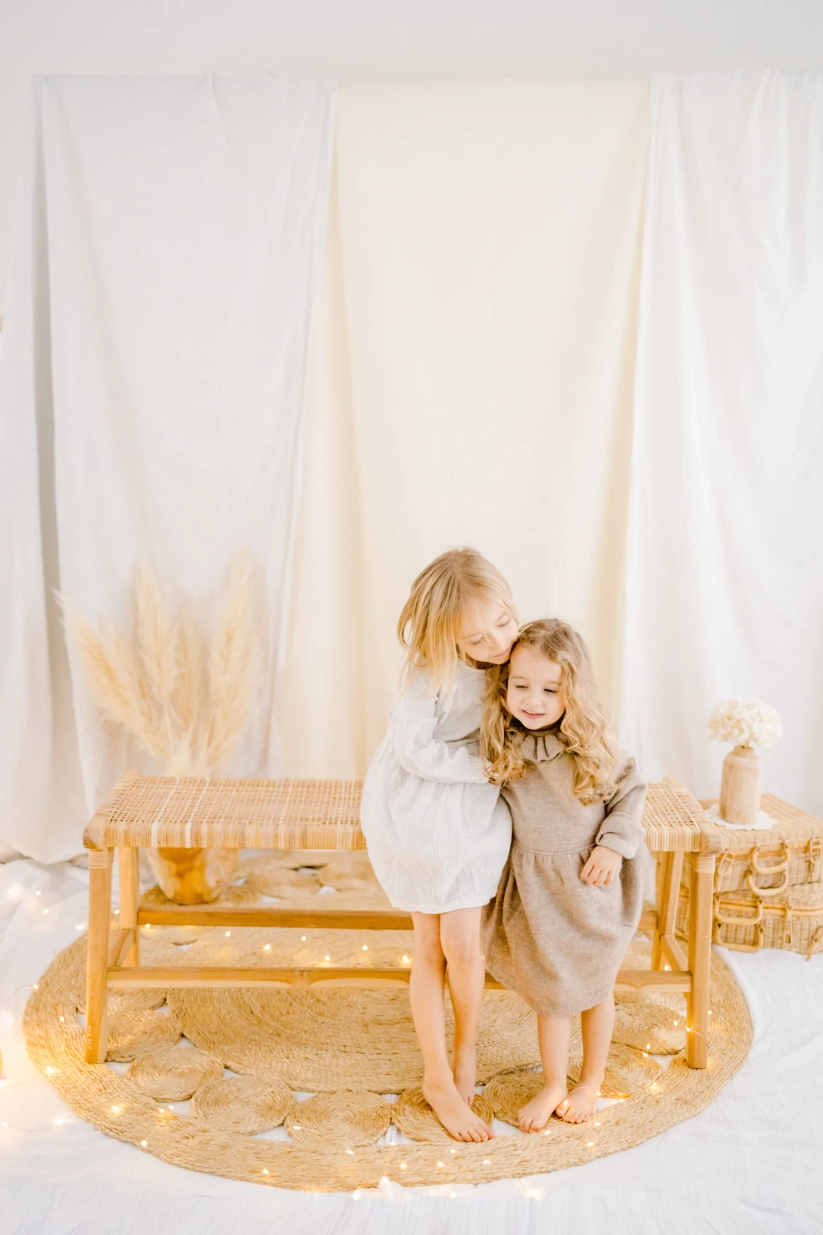 Séance photo famille avec deux jeunes enfants en complicité, ambiance douce et intemporelle, studio lumineux avec voiles blancs et décor épuré en Vendée