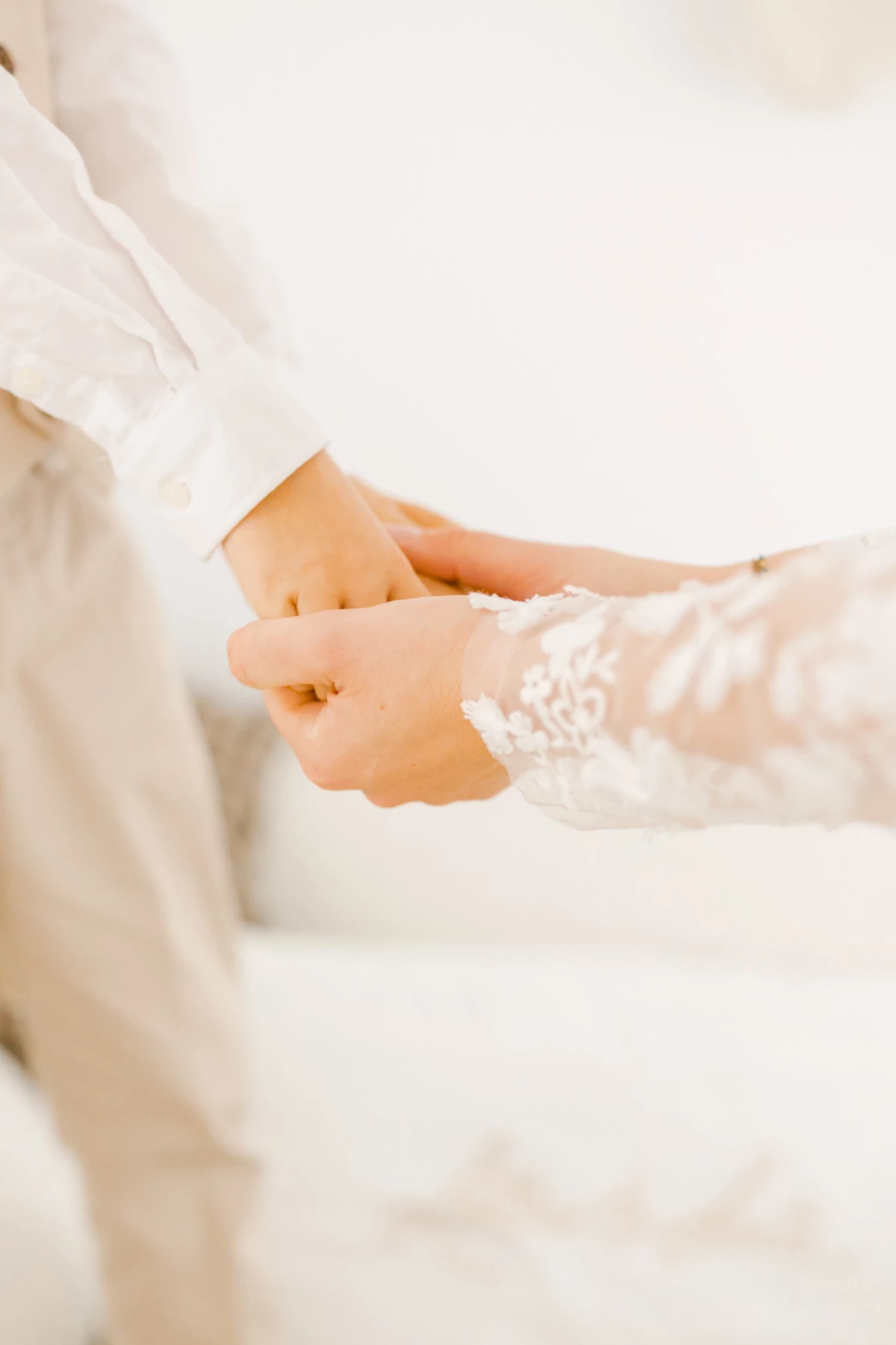 Gros plan sur les mains d'une mariée en robe blanche ornée de dentelle délicate