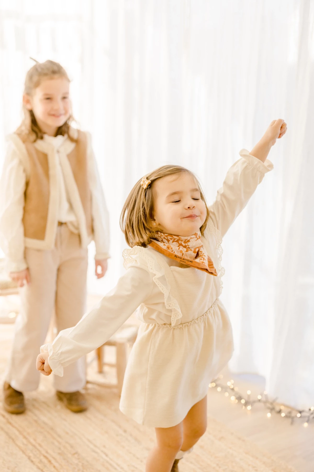 Séance famille en studio : petite fille danse avec joie en robe blanche, ambiance lumineuse et tendre, Vendée