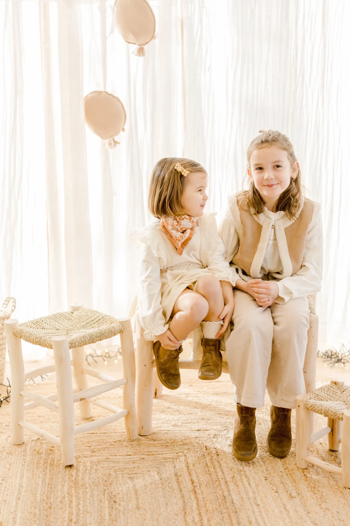 Séance famille en studio : deux sœurs assises côte à côte partagent un instant de complicité et de tendresse dans une ambiance douce