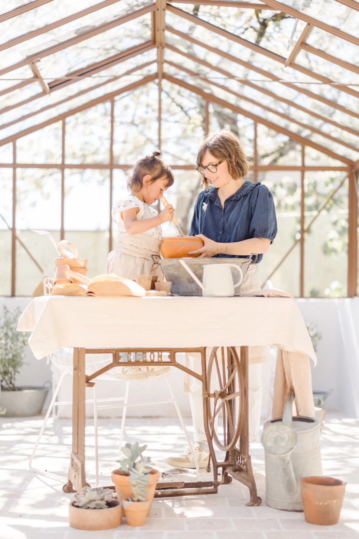 Séance famille en verrière : mère et fille partagent un atelier jardinage dans une ambiance douce et lumineuse en Vendée