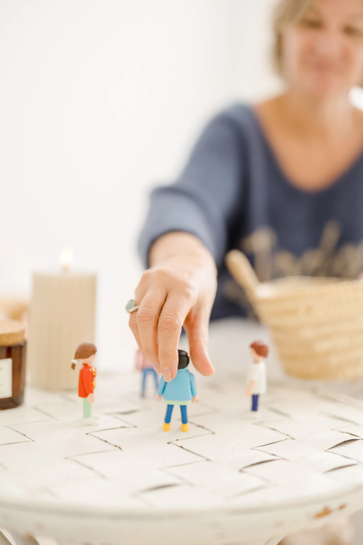 Main d'enfant manipulant de petites figurines en bois sur une surface claire