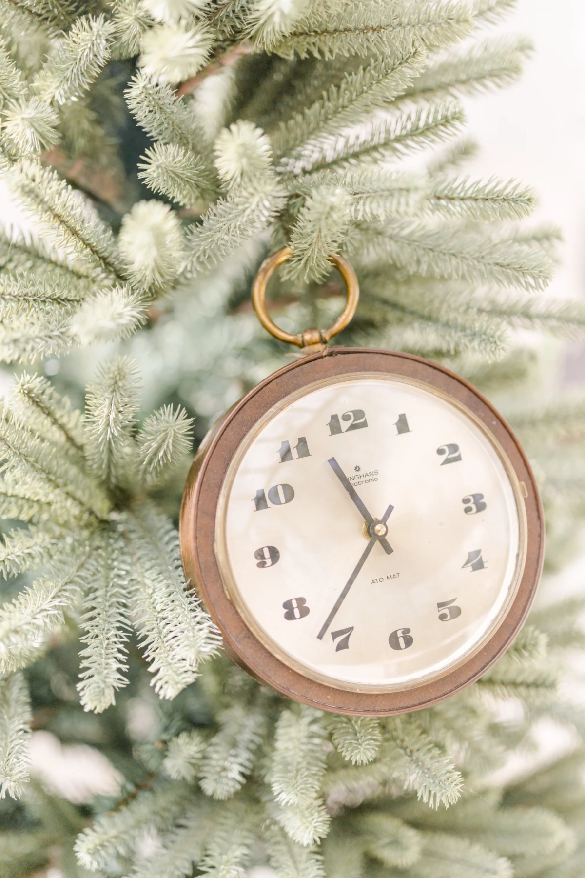 Décor séance Noël en studio : horloge vintage suspendue à un sapin givré dans une ambiance douce et intemporelle en Vendée
