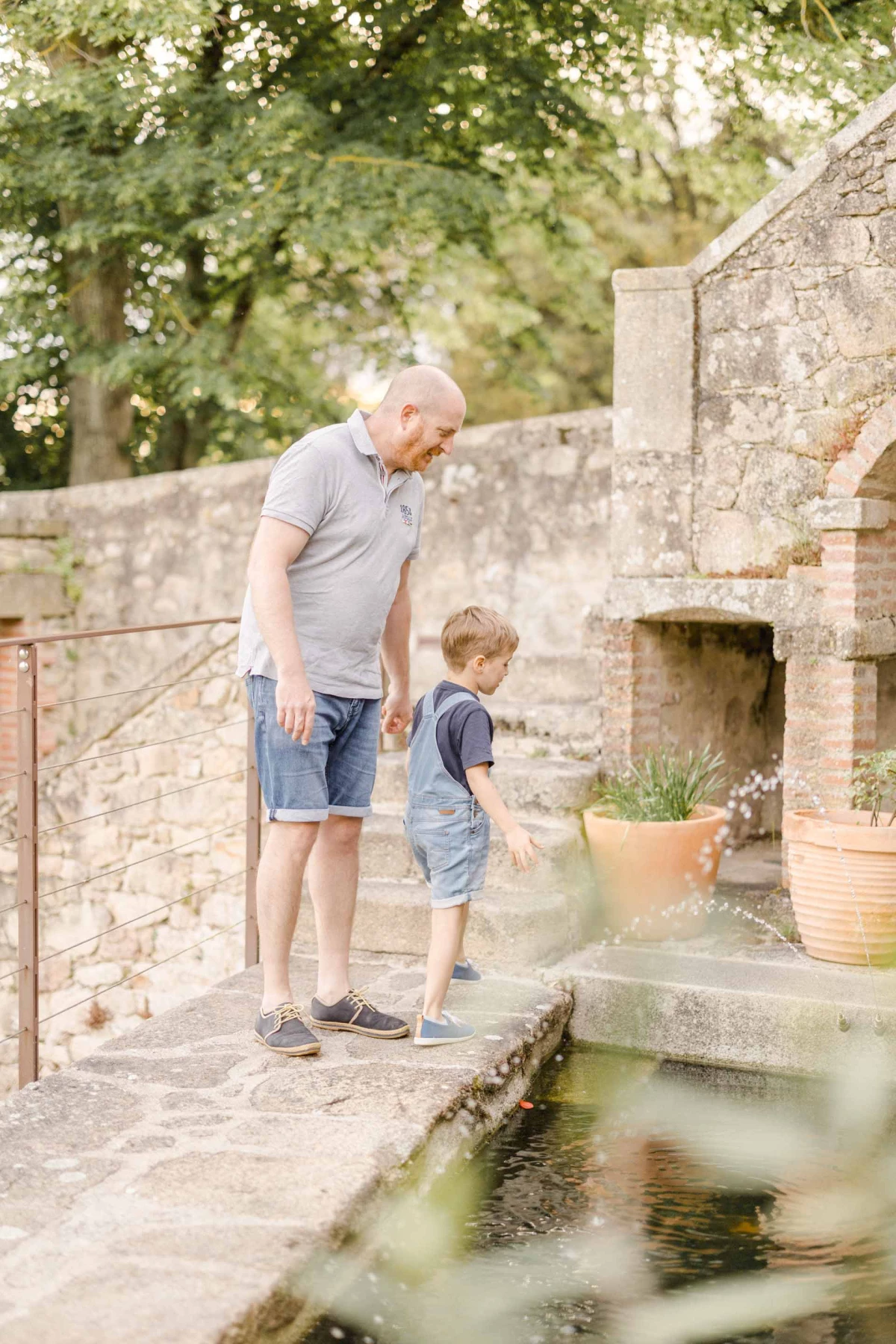 Grand-père et petit-fils observant ensemble un bassin ancien dans un jardin de château