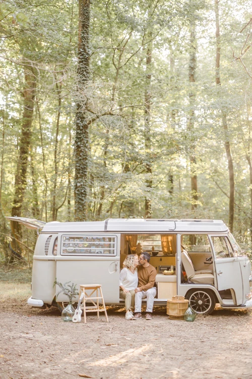 Séance famille dans un camping-car rétro en forêt, atmosphère chaleureuse et intemporelle avec lumière dorée filtrant entre les arbres