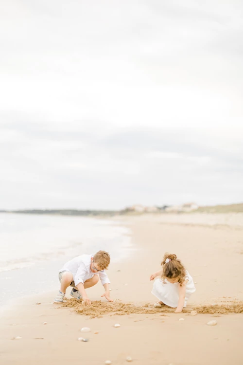 Deux enfants jouant ensemble dans le sable doré d'une plage, creusant avec leurs mains