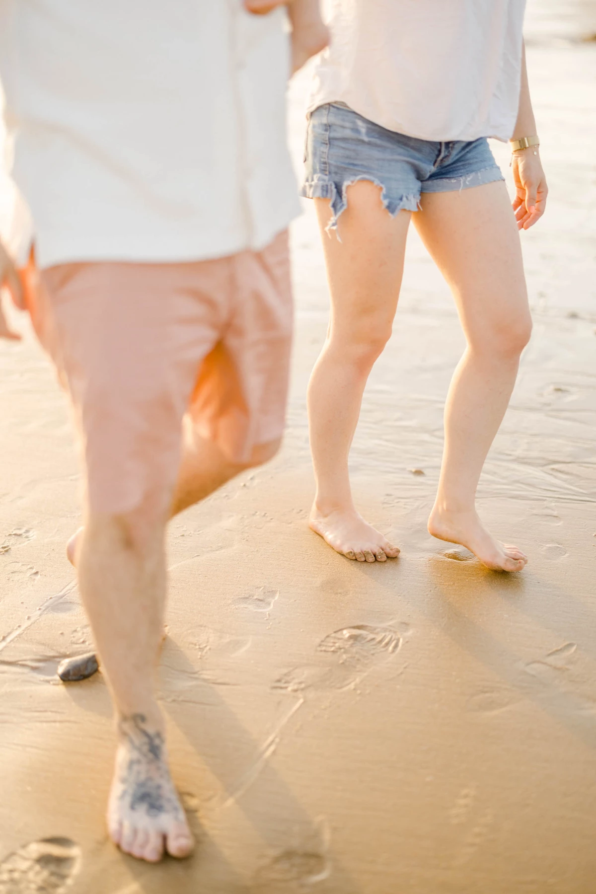 Famille marchant pieds nus sur le sable mouillé d'une plage au coucher du soleil