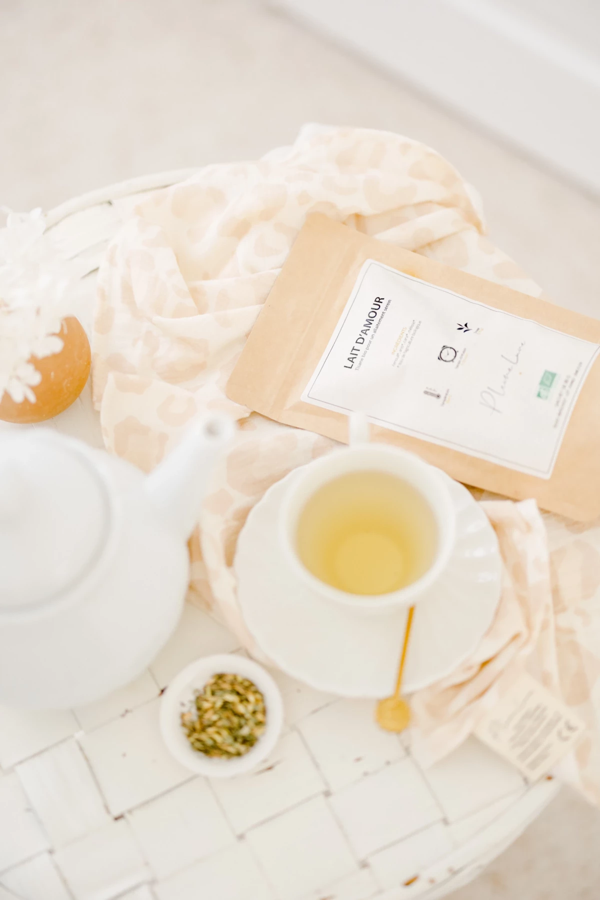 Tasse de thé clair et fleurs séchées disposées sur un linge beige, ambiance douce et naturelle