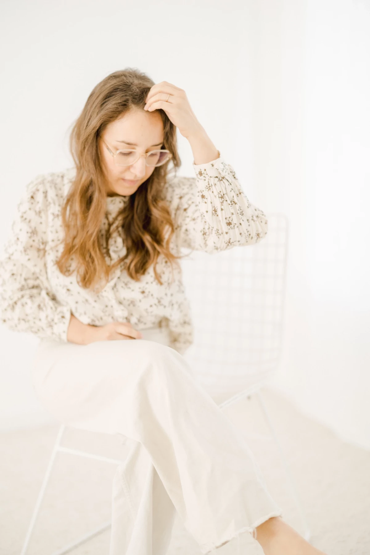 Portrait de femme assise en robe fleurie beige et jupe blanche vaporeuse sur fond clair