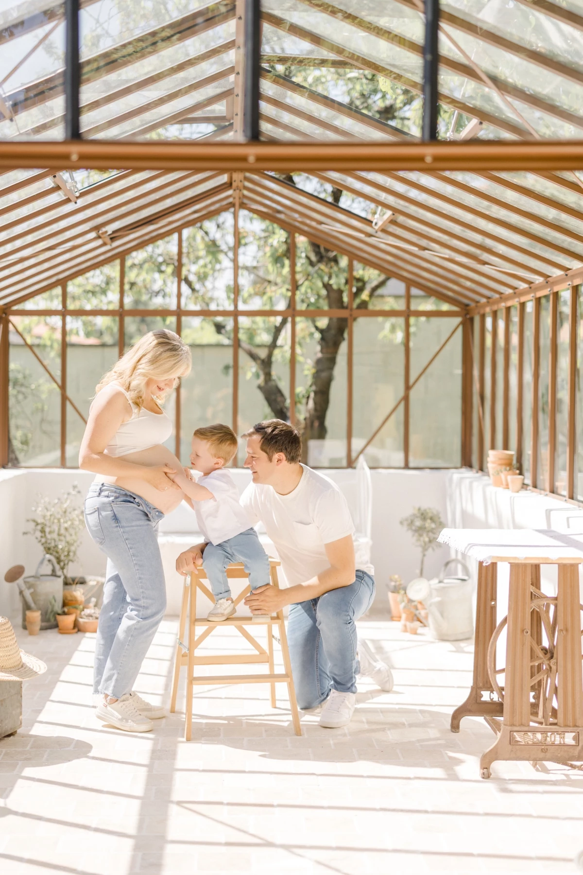 Séance famille en studio lumineux : parents et jeune enfant partagent un moment de complicité joyeuse dans une atmosphère douce et naturelle