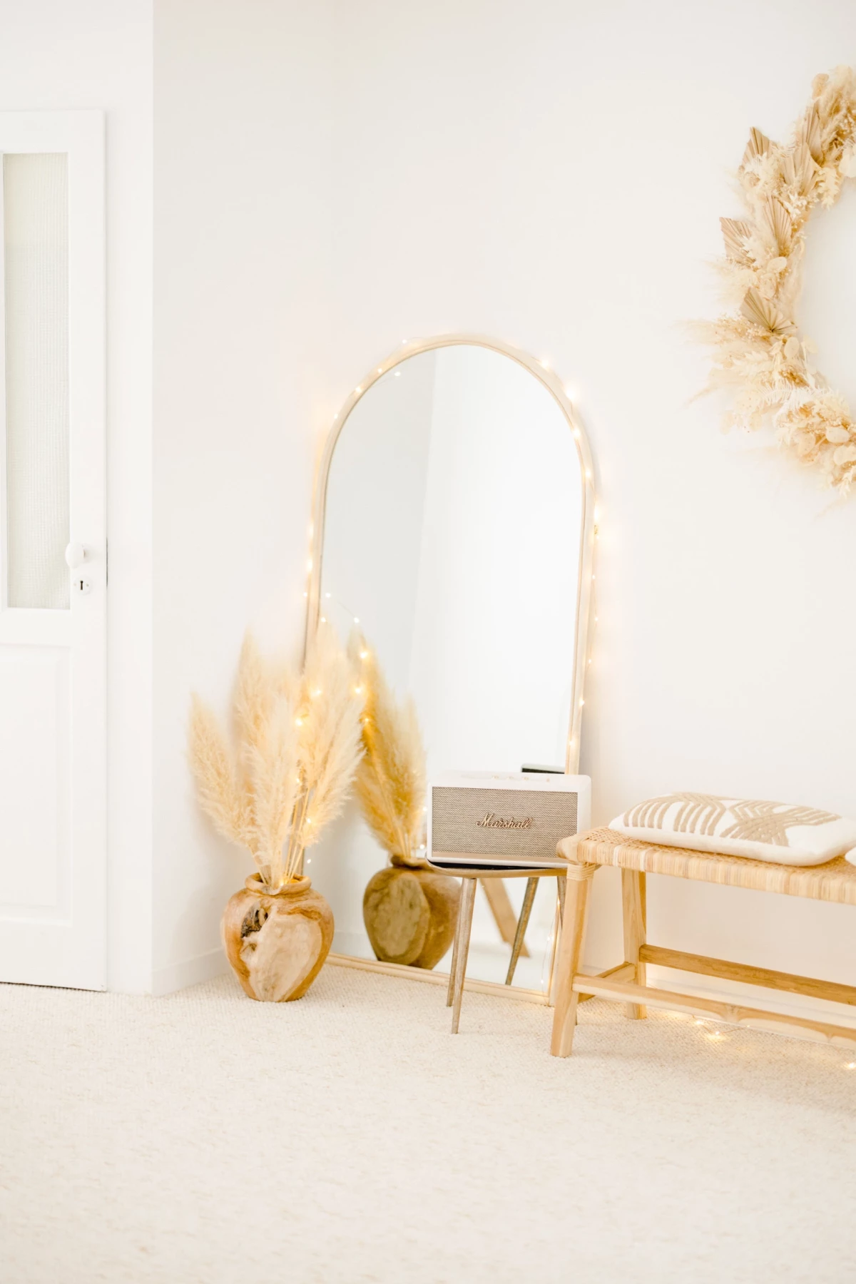 Miroir arche et banc en bois clair dans un décor minimaliste bohème avec pampas séchées beiges