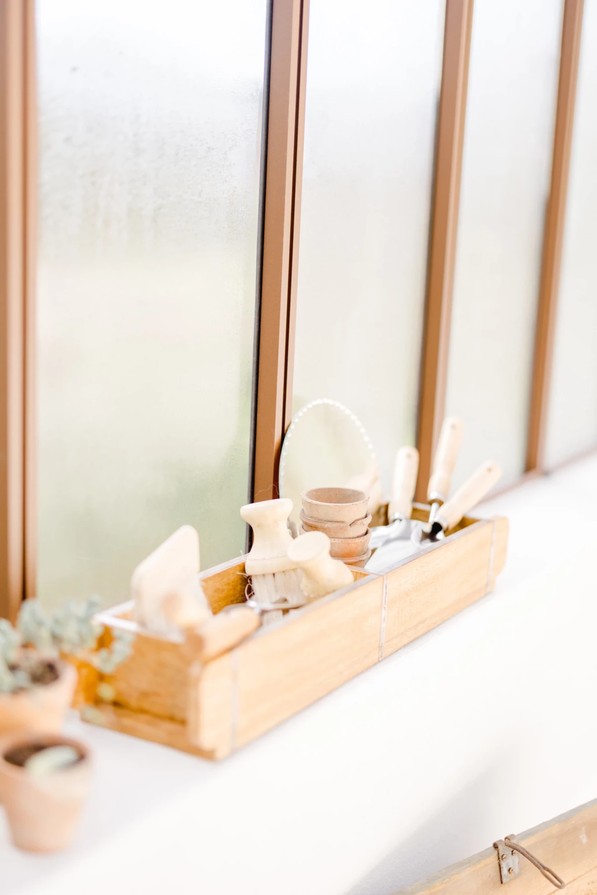 Plateau en bois avec accessoires de beauté naturels disposés près d'une verrière lumineuse