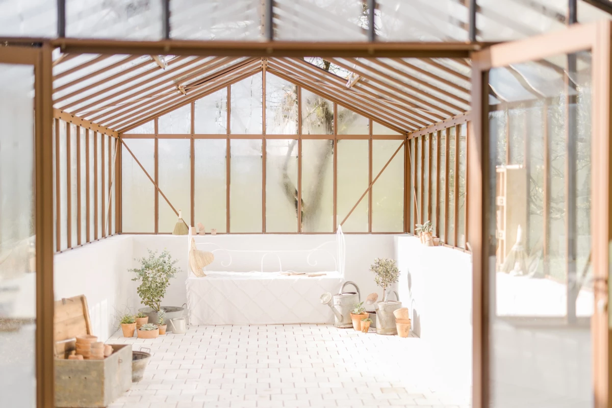 Décoration extérieur en Vendée : verrière bois intimiste, banc blanc fleuri dans une ambiance épurée et naturelle