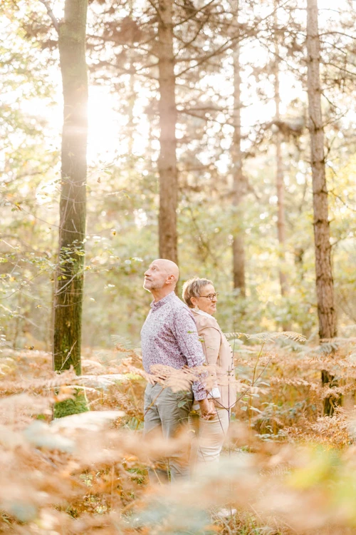 Séance couple en forêt : deux amoureux dos à dos dans une atmosphère automnale dorée, complicité naturelle en Vendée