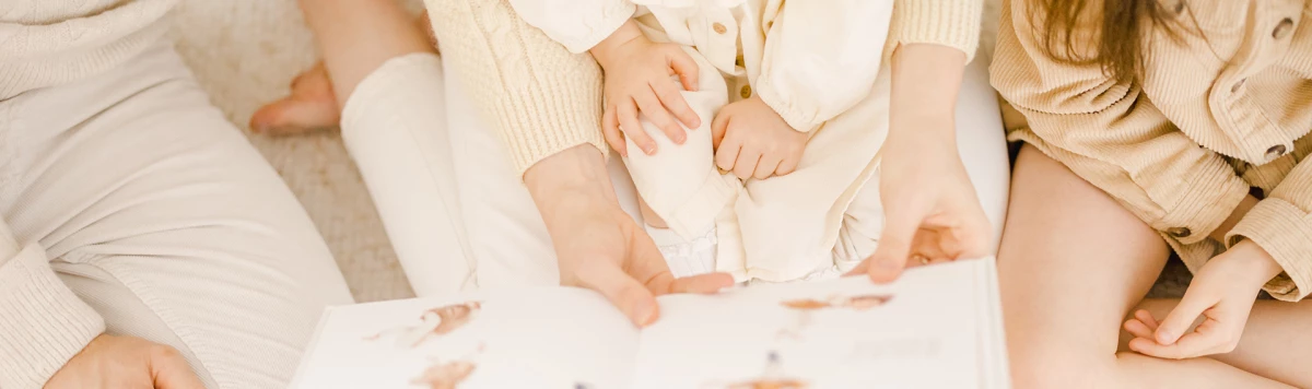 Séance photo maternité nouveau-né : famille enlacée en tenue beige clair, moment de tendresse et complicité sur fond neutre