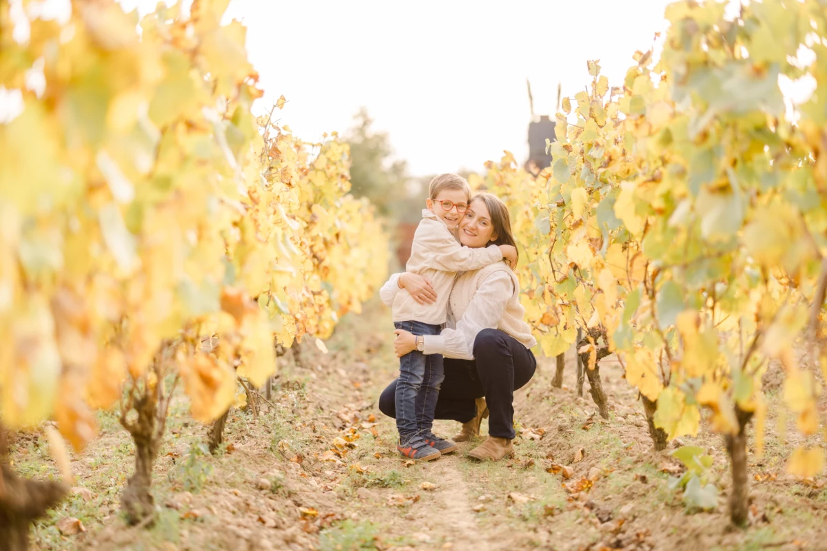 Mère et fils s'enlacent tendrement au milieu de vignes dorées en automne