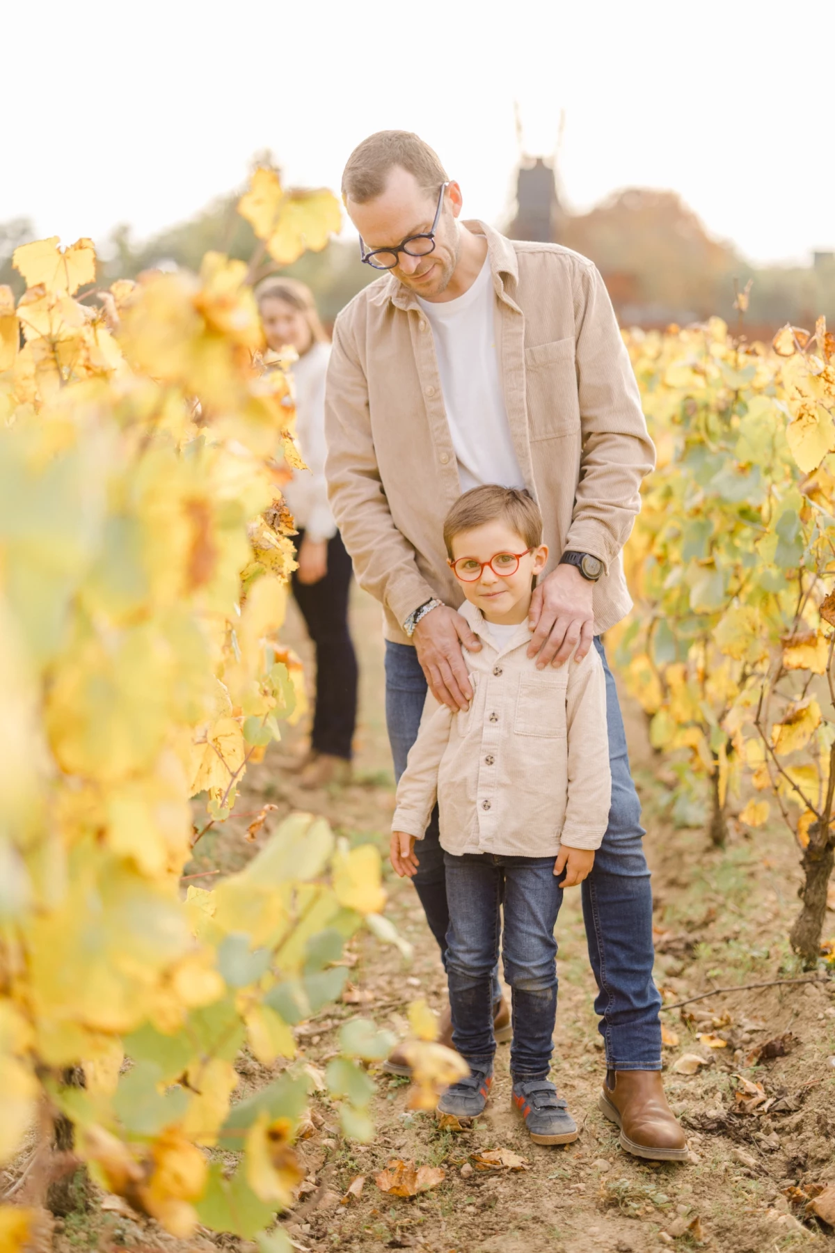 Père et fils complices marchant dans un vignoble aux teintes dorées d'automne