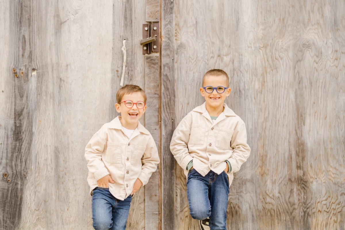 Portrait de deux jeunes garçons complices en chemise beige et jeans sur fond bois blanchi en studio