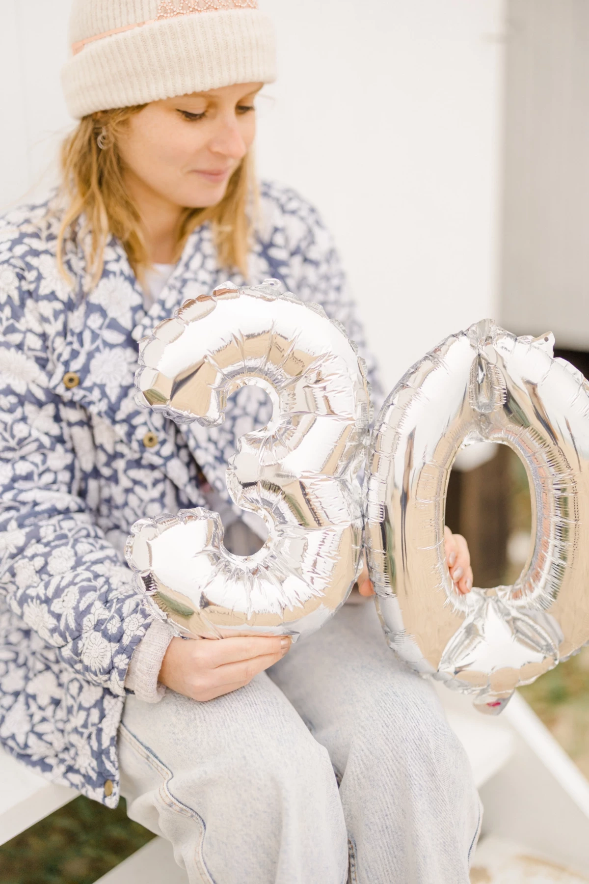 Femme tenant des ballons argentés formant le chiffre 30 pour célébrer un anniversaire en intérieur
